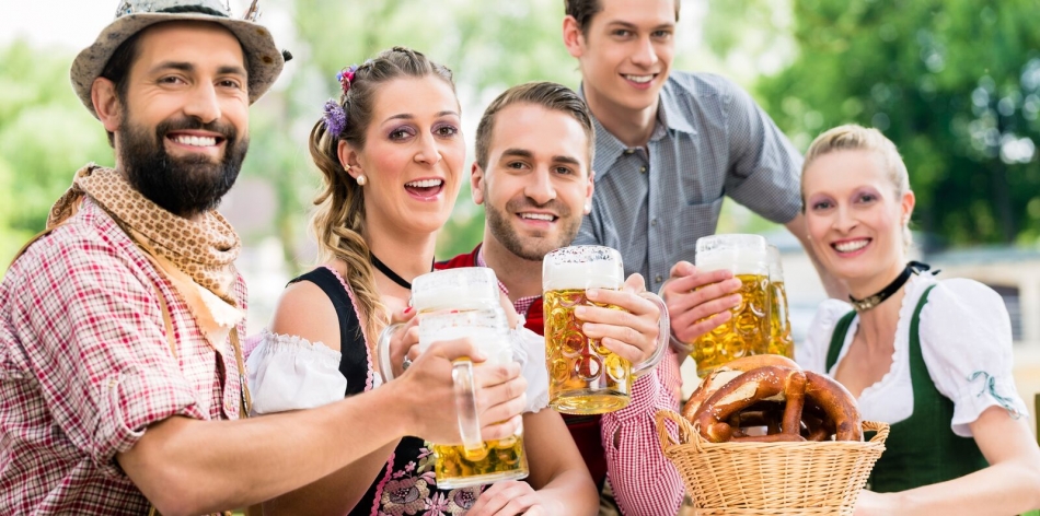 Fünf Teilnehmer in bayrischem Kostüm heben eine Maß Bier
